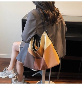 Lifestyle shot of large color-block hobo bag worn by model in a minimalist suit