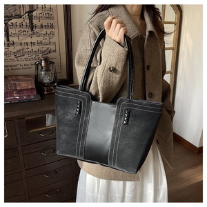 Detail of black vintage tote bag featuring contrast stitching and woven decorative accents