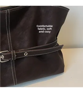 Détail du cabas en cuir litchi marron foncé avec coutures contrastées et boucle décorative
