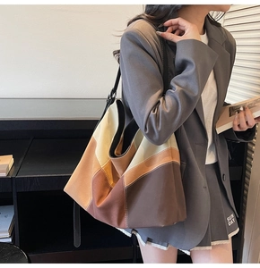 Detail of color-block canvas tote bag featuring geometric patchwork and wide shoulder strap