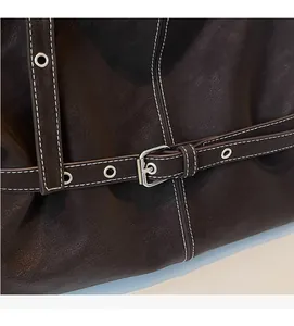 Détail du sac cabas en cuir marron foncé avec surpiqûres blanches et boucle en métal