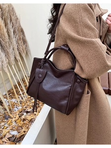 Detail of dark brown leather tote bag with tassels shown on a wool coat outfit