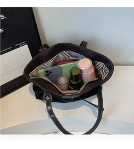 Vue intérieure d'un grand sac cabas noir montrant le rangement d'objets du quotidien