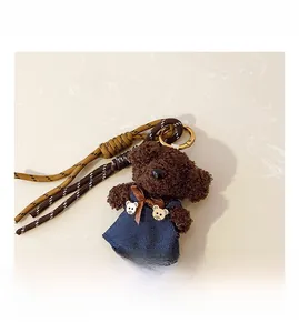 Detail of plush brown bear pendant with blue overalls and gold metal spring clasp