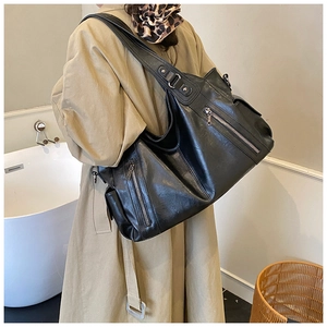 Close-up of a black oversized hobo bag showing soft leather texture and zipper details