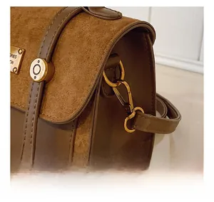 Detail shot of the golden metal hook and leather texture on a brown shoulder bag