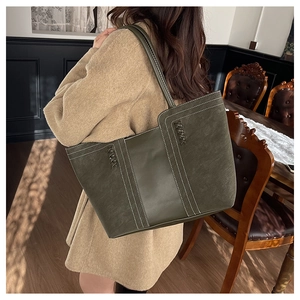 Detail of olive green tote bag featuring contrast white stitching and woven side texture