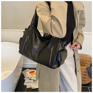 Detail of soft black PU leather handbag showing vertical zippers and pebble grain texture