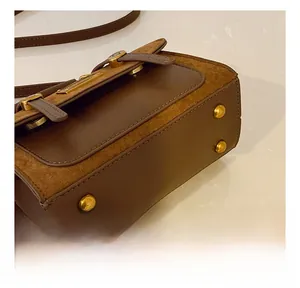 Detail view of the handbag bottom featuring smooth leather and four gold metal feet