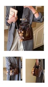 Detail of dark brown bucket bag with adjustable strap and cute plush bear charm