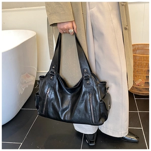 Detail of black large capacity shoulder bag showing soft leather texture and side pockets