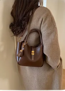 Detail of vintage brown shoulder bag showing golden square lock and leather pendant