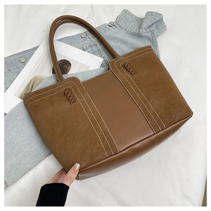 Detail of vintage brown tote bag showing mixed textures and contrast white stitching
