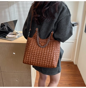 Macro detail of brown quilted tote bag showing texture, silver chain and leather strap