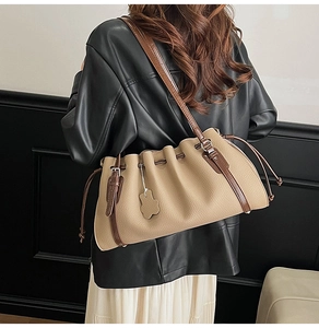 Detail of pleated shoulder bag featuring vintage metal buckle and cute bear charm