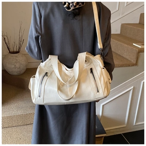 Detailed view of the cream leather shoulder bag with decorative zippers and wide handles