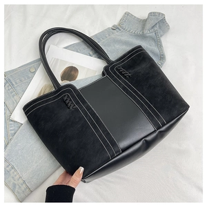Detail of black tote bag with white contrast stitching and faux leather patchwork design