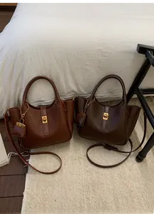 Close-up of litchi texture leather handbags with golden twist lock and mini pouch charm
