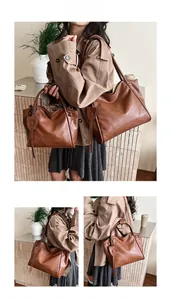 Detail view of large brown soft leather tote bag with leaf charm charm and button closure