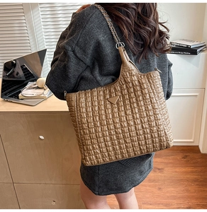 Detailed view of brown quilted pleated leather tote bag with chain strap and metal detail