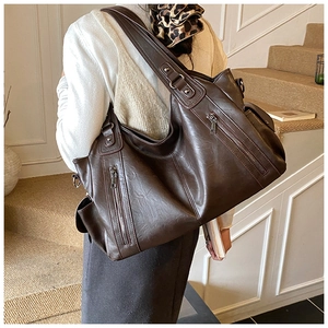 Detail of dark brown faux leather tote bag with functional gold zippers and pebble texture