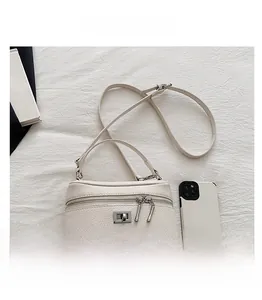 Detail view of cream leather crossbody box bag with dual zippers and silver twist lock