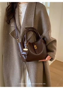 Close-up of retro brown leather shoulder bag with gold clasp and mini pouch accessory