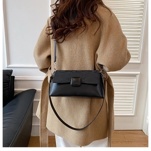 Detail einer minimalistischen schwarzen Umhängetasche getragen zu einem camel Wollmantel