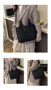 Close-up of black quilted leather tote bag featuring a silver chain strap and metal badge