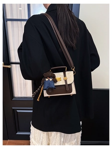Detail of canvas crossbody bag with leather trim and cute brown bear charm