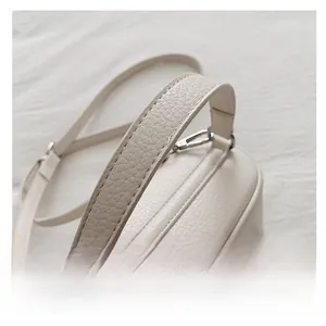 Detail view of cream-colored lychee pattern leather handbag with silver hardware and strap