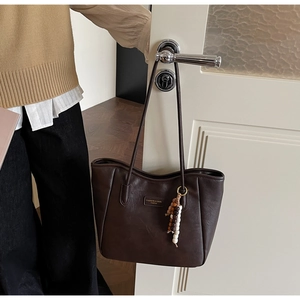 Close-up of dark brown tote bag with smooth texture and stylish beaded tassel detail