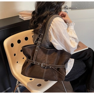 Détail de cabas marron foncé avec surpiqûres blanches contrastées et boucles de ceinture