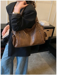 Brown leather tote bag with vertical zipper pockets shown in lifestyle scene
