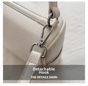 Detail of silver metal lobster clasp and detachable strap on white pebbled leather handbag