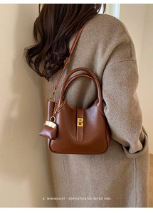 Close-up of minimalist retro tote bag with golden twist lock and metallic chain detail