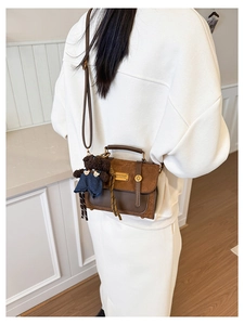 Detail of vintage brown crossbody bag featuring a cute teddy bear plush charm attachment