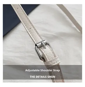 Detail of adjustable off-white lychee leather shoulder strap with silver metal buckle