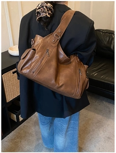 Detailed view of brown faux leather shoulder bag with metallic zipper pockets and soft texture