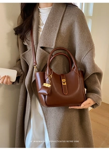 Detail of retro brown leather tote with gold twist lock and mini purse charm on wool coat