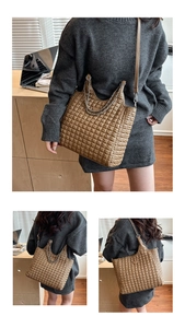 Detail of brown quilted leather tote bag with silver chain handle and metal triangle plate