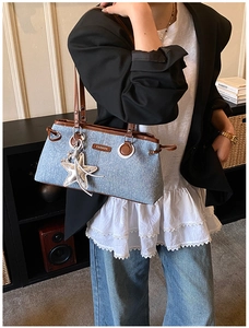 Détail du sac bandoulière en denim avec garniture en cuir brun et pendentif étoile de mer