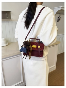 Model wearing a burgundy vintage dual-texture backpack with a cute bear pendant