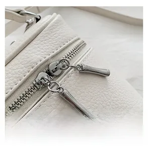 Close-up of white lychee leather handbag with premium silver dual zippers and fine stitching