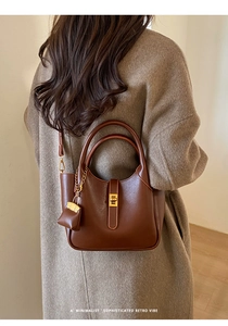 Detail of retro brown leather handbag with gold twist-lock and decorative mini charm
