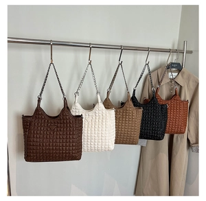 Detail of diverse tote bags featuring quilted textures and elegant chain shoulder straps