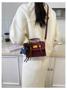 Detail of burgundy vintage crossbody bag with plush bear charm and golden hardware