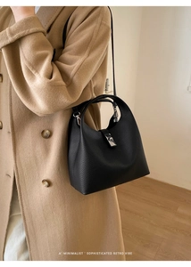 Chic black litchi pattern bucket bag with silver lock worn with a camel coat