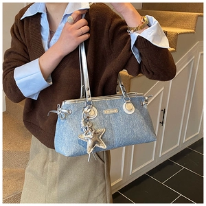 Détail d'un sac à épaule en jean bleu avec quincaillerie argentée et pendentif étoile