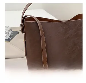 Dettaglio della tracolla regolabile su una borsa a secchiello in pelle marrone scuro